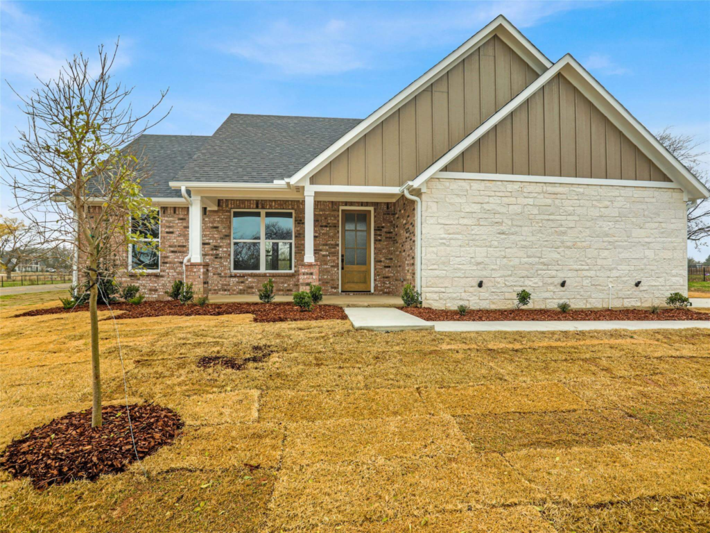 The inviting front porch of the Westlake Home in the DFW metroplex by Northwood Homes, featuring a craftsman-style wood door and traditional brick masonry.