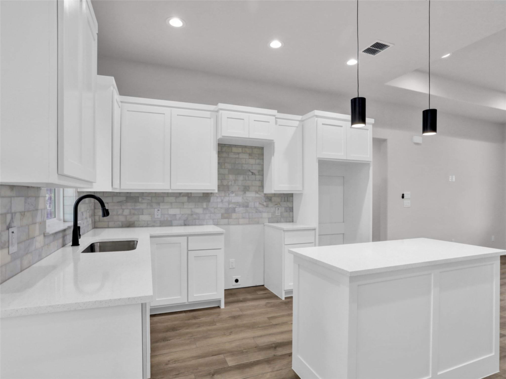 Modern custom kitchen featuring white cabinetry, a large central island, and contemporary pendant lighting.