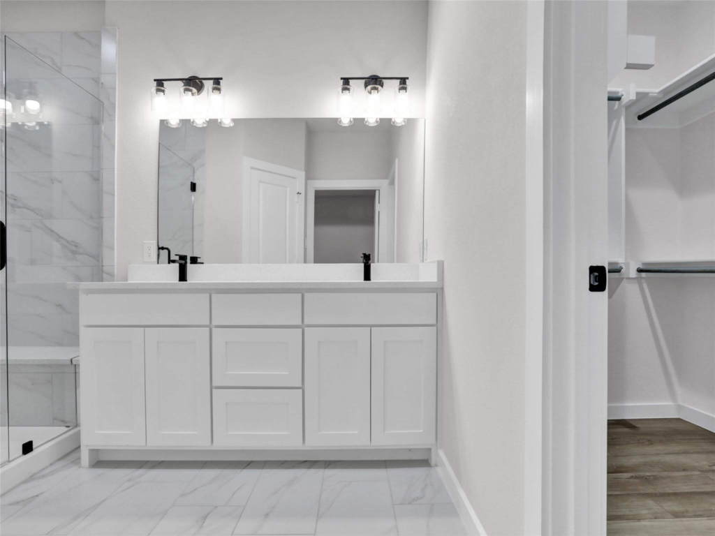 A luxurious primary bathroom with a double vanity and floor-to-ceiling marble tile shower by Northwood Homes.