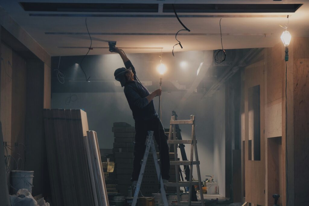 A craftsman installing electrical wiring in the open frame of a custom-built residence.